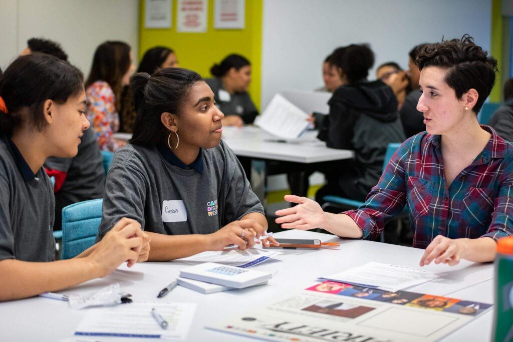 A mentor guiding students through discussion and workbook activities during a Being Built session